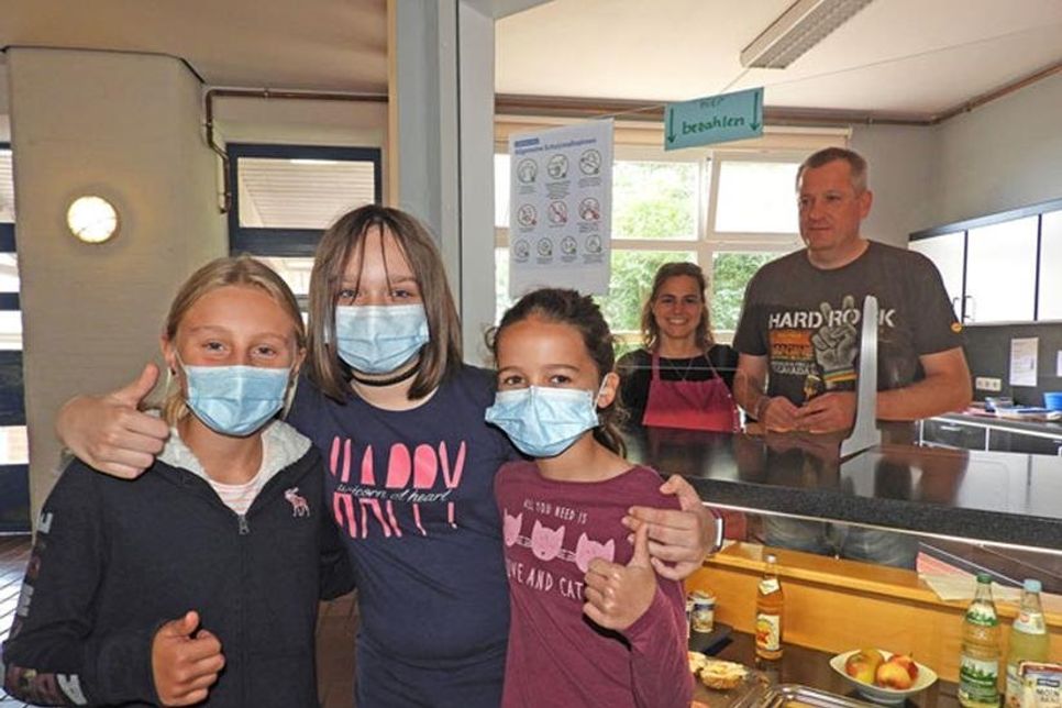 Endlich wieder Schule: Da sind sich Tosca, Melissa und Marisa aus der 6b der Voss-Schule einig. Und hinter dem Spuckschutz von „Heinrichs Essbar“ stimmen Nadine Schwarzmann und Björn Kohlwes, der auch Vorsitzender des Elternbeirates ist, zu.