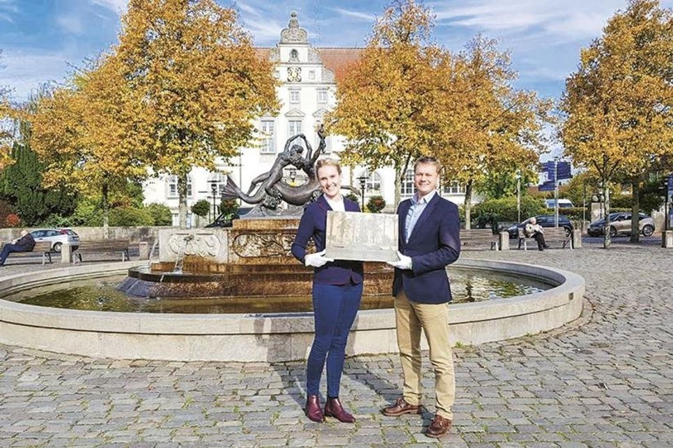 Bürgermeister Dr. Uwe Brinkmann und Museums- und Kulturmanagerin Judith Ohrtmann mit einer beispielhaften Fotografie. Damals wie heute ist der Brunnen mit dem Amtsgericht im Hintergrund ein beliebtes Fotomotiv.
