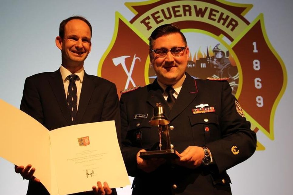 Staatssekretär Torsten Geerdts (lks.) überreichte Gemeindewehrführer Alexander Wengelewski eine Ehrenurkunde und eine goldene Glocke.