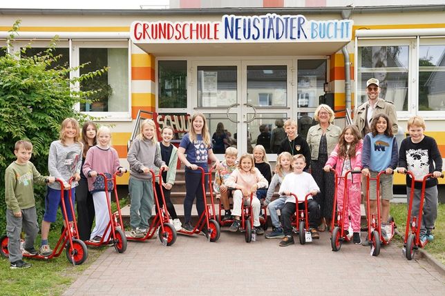 Kevin Neubaumer übergab sieben Roller und zwei Dreiräder an die Grundschule Neustädter Bucht, die die Kinder der Klasse 3e und Schulleiterin Antje Sagawe freudig in Empfang nahmen.