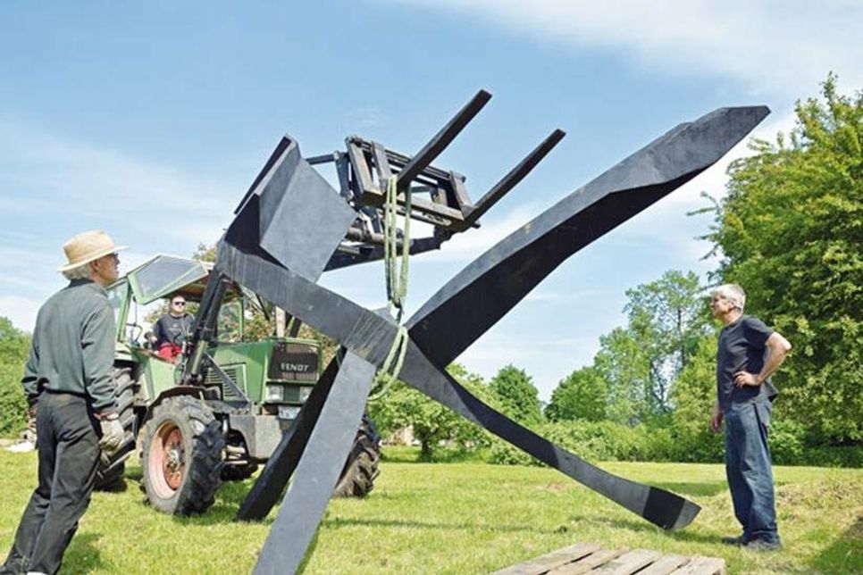 Kunst am Haken: Im Skulpturenpark Seeweg haben Rüdiger Sartory vom Gut Wittmoldt und Künstler Uwe Gripp (v. l.) mit Hilfe des Frontladers die Apokalyptischen Reiter von Jan Koblasa aufgestellt.
