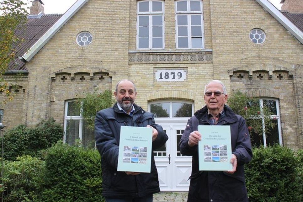 Bürgermeister Lutz Schlünzen (lks.) und Uwe Stock mit dem Chronik der Gemeinde Beschendorf vor dem ehemaligen Inspektorenhaus und Verwaltergebäude des Gutes Nienrade.