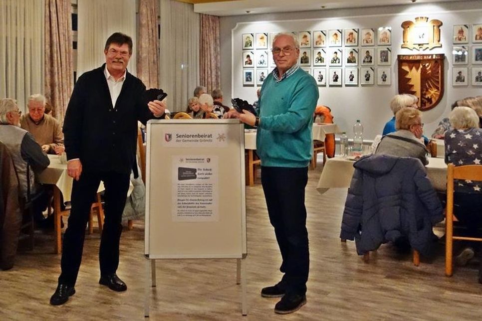 Rainer Figgen (Vorsitzender des Seniorenbeirats, re.) und Michael Suhr (Helfer und Wahlkandidat) präsentieren die neuen Schutzhüllen.