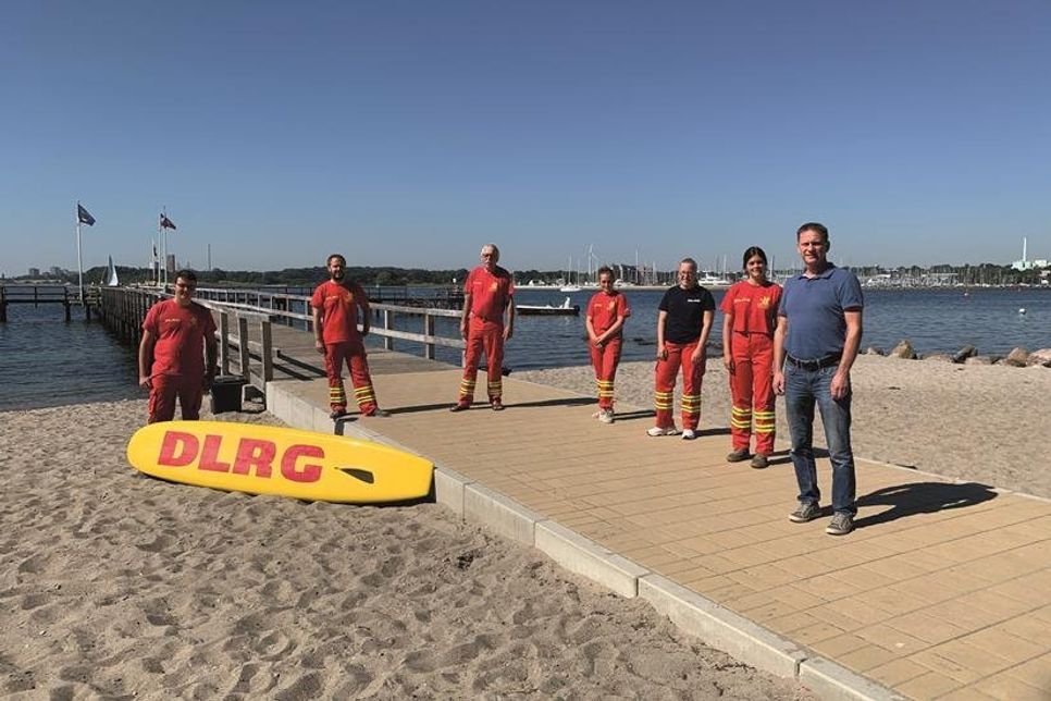 Übergabe von Einsatzhosen an den Wasserrettungsdienst der DLRG Neustadt durch Andreas Schneider (re.) vom Amt für gesellschaftliche Angelegenheiten.