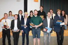 12 Auszubildende des Tischlerhandwerks halten stolz ihren Gesellenbrief in der Hand.