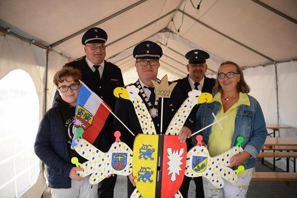 „Hans Holzfäller“ hieß der Vogel in diesem Jahr. Der bis dato amtierende Schützenkönig Kai Peter Liedtke (mi.) mit Familie sowie Wehrführer Hans-Werner Landschoof (2. v. lks.) und Vogelbauer Sven Ketturkat (2. v. re,) präsentieren das gute Stück.
