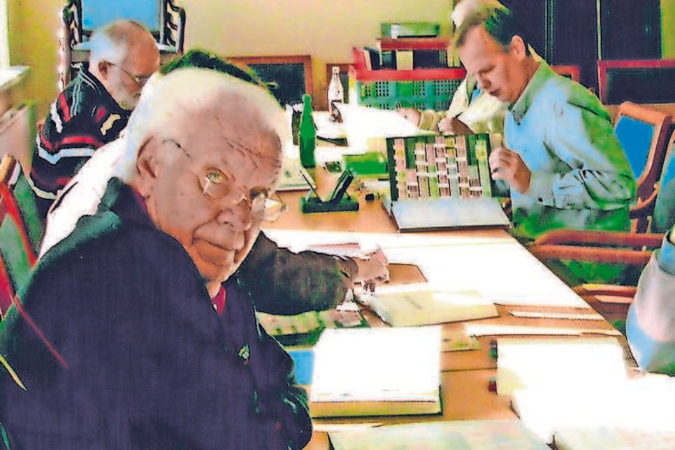 Briefmarkensammler beim Durchschauen von Katalogen.