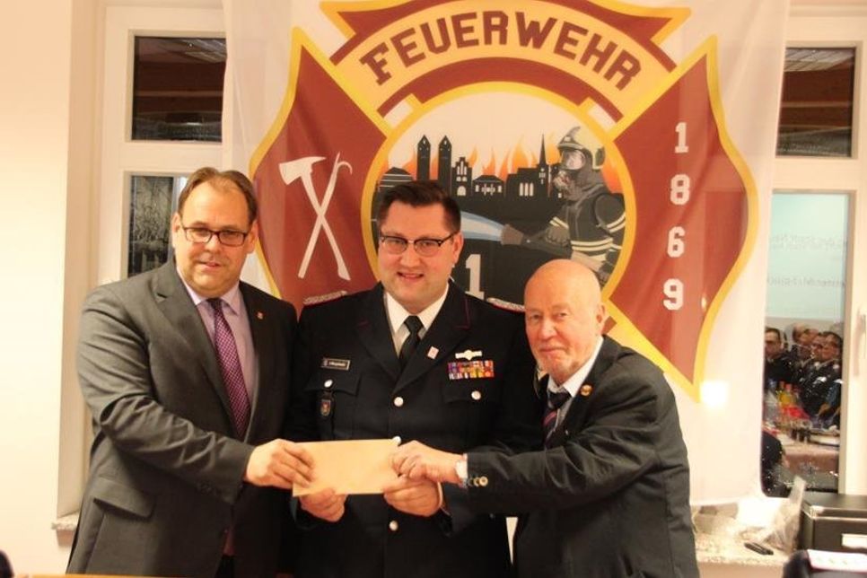 Bürgermeister Mirko Spieckermann (lks.) und Bürgervorsteher Sönke Sela (re.) übergaben ein "Flachgeschenk an Wehrführer Alexander Wengelewski bei der Jahreshauptversammlung der Freiwilligen Feuerwehr Neustadt.