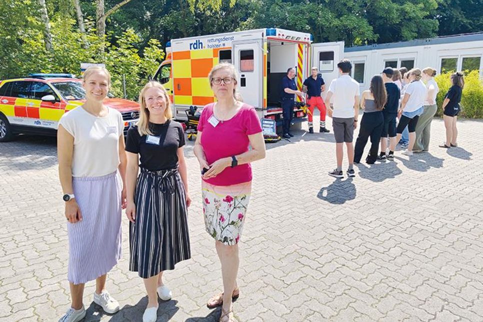 Isabelle Schröder, Koordinatorin für die Berufliche Orientierung am OGT (von links), ihre Kollegin Daniela Ronneberger und Schulleiterin Dr. Cordula Braun freuen sich über den erfolgreichen 3. Berufe-Tag. Im Hintergrund informieren sich Schüler beim Rettungsdienst Holstein über Notfallmedizin.