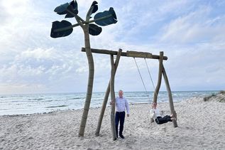 „Auf die Schaukel, fertig, los!“: Jacqueline Schumacher vom Tourismus-Service Grömitz und Manfred Wohnrade zeigen am neuen Standort an der Wiese Uferstraße, wie viel Spaß die beliebte Grömitz-Schaukel mit Ostseeblick macht.
