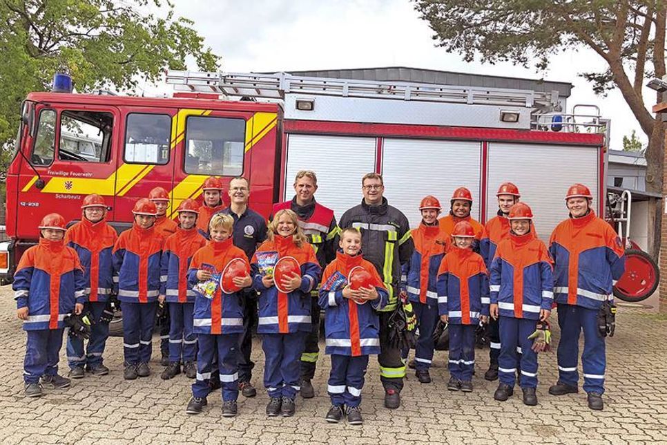 Die drei neuen Jugendlichen aus der Kinderfeuerwehr (vorne mit Helm in der Hand), dahinter (von links) David Siegmund, Leiter der KFS80, Sebastian Levgrün, Ortswehrführer der FFS80, und Marc Rollmann, Jugendwart der JFS 80, dahinter das Team der JFS 80.  (Foto: FFW)