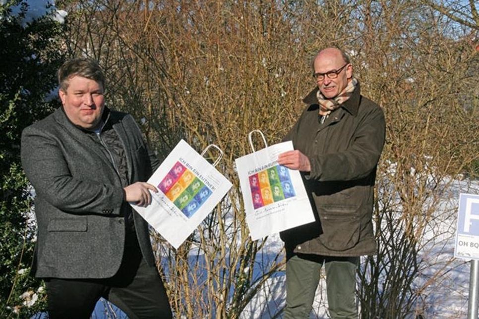 Falk Herzog und Hans-Wilhelm Hagen (WVE) präsentieren die mit Webers Portrait bedruckten Eutiner Einkaufstaschen.