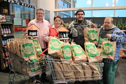 Nahkauf-Mitarbeiter Nils Burk-Meier (lks.) und Marktleitung Susanne Doose bei der Übergabe der Lebensmittel-Tüten an die Tafel-Helfer Michael Bünning und Andreas Gumgowski (re.).