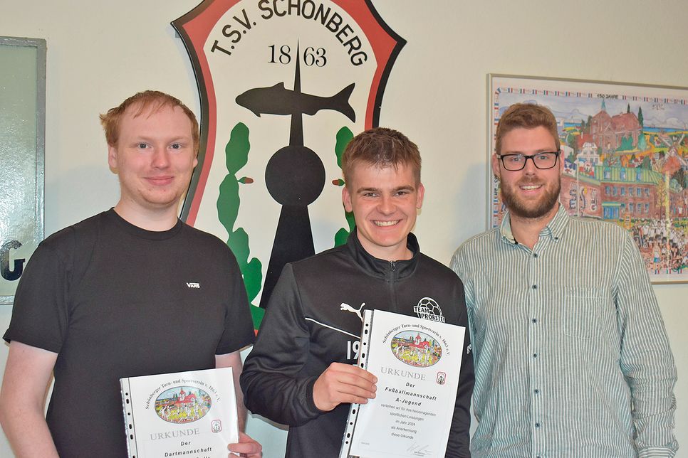 Der 2. Vorsitzende Lars Lindau (r.) ehrt Justus Schröder (A-Jugend Team Probstei) und Maximilian Wildfeuer (Dart Team Beach Bulls) für die Aufstiege ihrer Mannschaften in die Landesliga bzw. Oberliga.