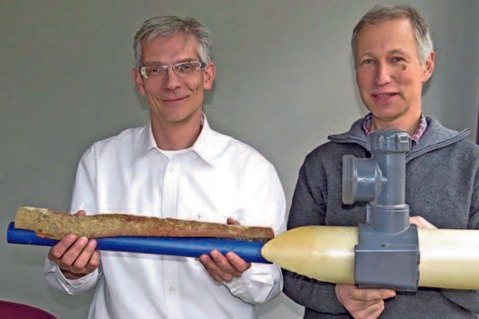 Olaf Bennühr von den Gemeindewerken Malente (l.) mit dem "Corpus Delicti" –  einer Baumwurzel, die sich an einer Wasserleitung entlang hangelte. Frank Petzold von SH Netz zeigt ein PVC-Rohr mit Anschlussmuffe, wie es in der Bismarckstraße verbaut wurde.