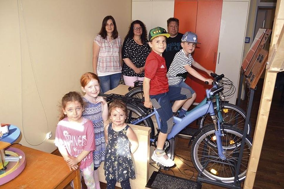 Nele (vorne v.l.), Ronja und Zoé sind ebenso begeistert von den tollen Experimenten wie Lasse und Til, die kräftig in die Pedalen treten, um Strom zu erzeugen. Im Hintergrund schauen sich Gruppenleiterin Agnieszka Staunicka (l.) und Doreen Hartung (FAW) mit  dem Erbauer des Exponats, Michael Siebert, das gelungene Experiment an. (Foto: Stefan Setje-Eilers)