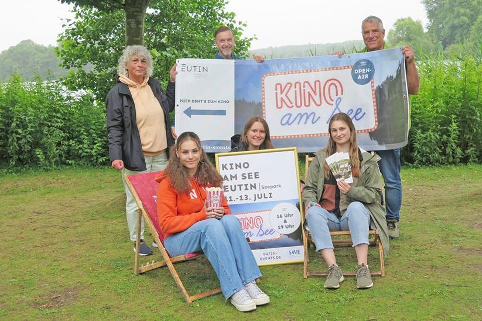 Sommerzeit ist Kinozeit im Seepark in Eutin. Und auch in diesem Jahr wartet ein Programm mit Spaß und Unterhaltung für alle Generationen. Während Eva Staege, Michael Keller und Torsten Medloff (stehend v. l.) von der Touristik-GmbH das Werbe-Banner und Auszubildende Kimberly Schoering das Plakat für das „Kinoevent am See“ präsentieren, haben sich mit Victoria Meier und Lara Kuhlmann zwei weitere Auszubildende fürs Pressefoto in den Liegestühlen platziert.