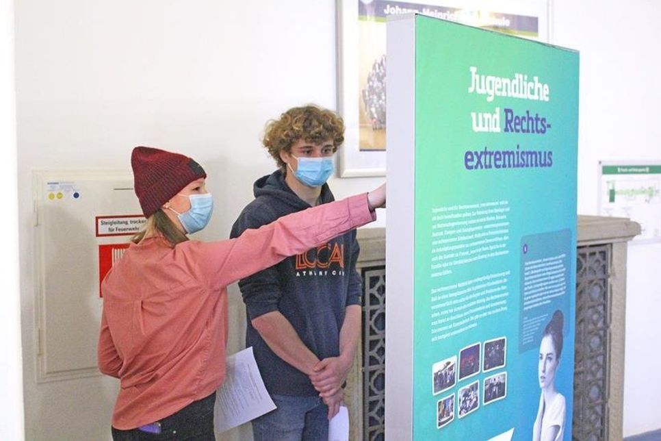 Hannah und Luis an dem Aufsteller über die Gefahren, die Rechtsextremismus bereits für Jugendliche bergen kann