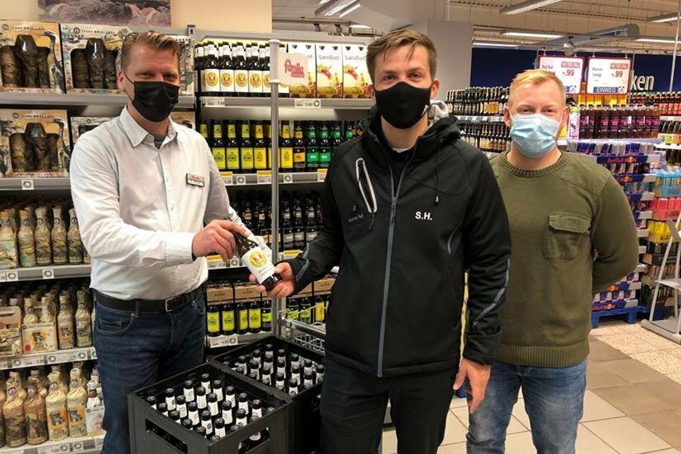 famila-Warenhausleiter Mathias Affeldt (lks.) überreichte die symbolische „Spendenflasche“ an Sascha Herz und Philip Horn vom TSV Neustadt (v. lks.).