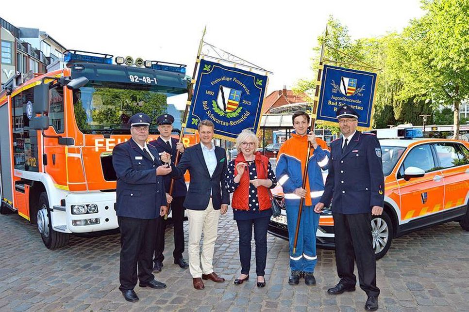 Unter den neuen Fahnen der Freiwilligen Feuerwehr Bad Schwartau-Rensefeld übergaben Bad Schwartaus Bürgermeister Uwe Brinkmann und Bürgervorsteherin Birgit Clemens die Fahrzeugschlüssel an Ortswehrführer Olaf Dreyer (l.) und Gemeindewehrführer Lars Wellmann (r.). (Foto: Setje-Eilers)