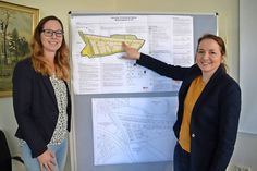 Timmendorfer Strands Bauamtsleiterin Meike Piechotta (links) und Bürgermeisterin Hatice Kara vor dem Bebauungsplan, der das Niendorfer Neubaugebiet „Blumenkoppel“ darstellt.