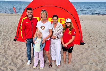 DLRG-Geschäftsführer Lukas Reuter mit Küstenlady Heike Möller und Patenkind Ida, Bürgermeisterin Bettina Schäfer und die ehrenamtliche DLRG-Rettungsschwimmerin Leila.
