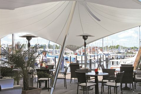 Herrliches Ambiente: eine der beiden Terrassen zwischen Restaurant, Palmen und Segeln.