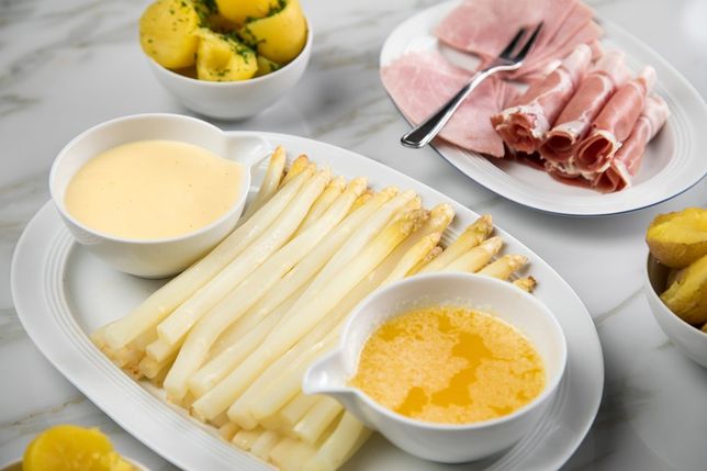 Klassisch serviert: Frischer weißer Spargel mit Sauce Hollandaise, zerlassener Butter, Kartoffeln und Schinken.