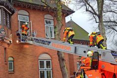 Zwei Kameraden mit Atemschutzgeräten steigen über die Drehleiter in das Obergeschoss