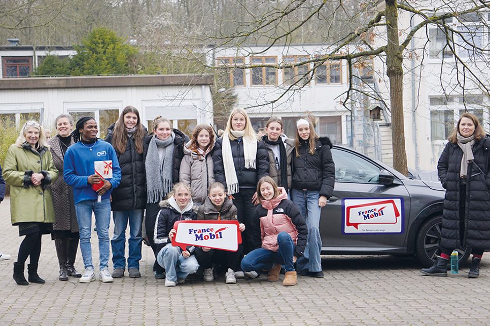 Dagmar Schmidt (langjährige Französischlehrkraft am OGT, von links), Schulleiterin Dr. Cordula Braun, Jean Christian Kakpo (Lektor/FranceMobil), Schülerinnen der Jahrgangsstufe 9 und Französischlehrerin Anna-Sophie Wilkes vor dem FranceMobil.