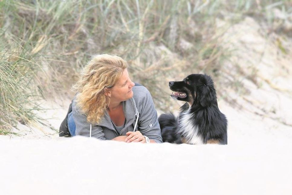 Sandra Reil am Strand mit „Pepper“, einem Mini Australian Shepherd.