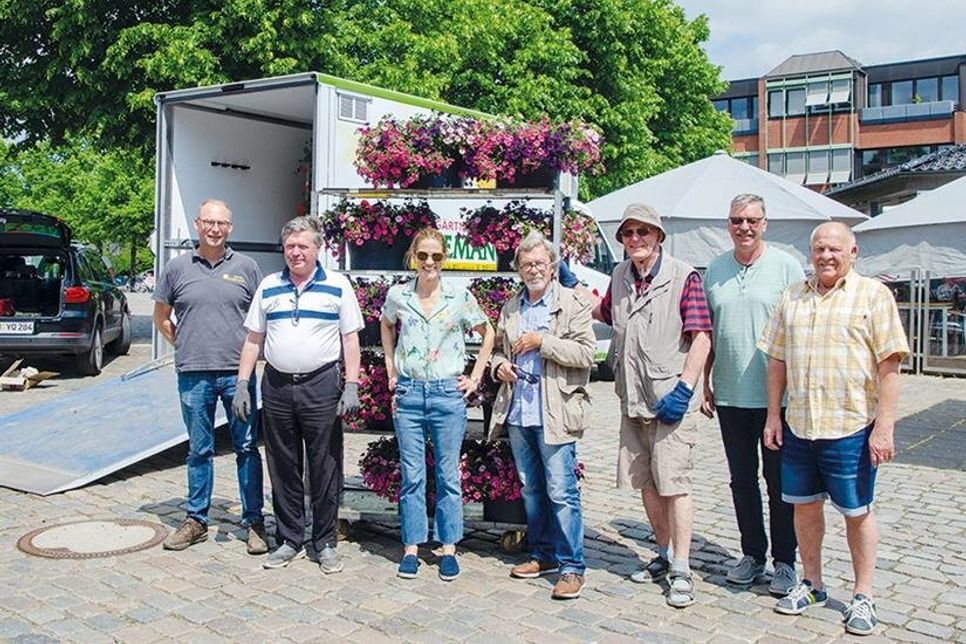 Die fleißigen Helfer stehen zum Aufhängen der Blumenampeln bereit.