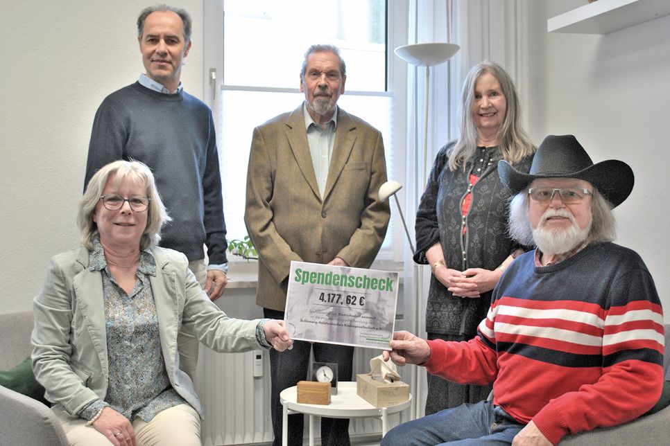 „Sheriff“ Uwe Göllner (Line-Dancer Gruppe Kiel, v.r.) überreicht einen symbolischen Scheck über rund 4.200 Euro an Annkatrin Rogge. Mit dabei waren (dahinter, v.l.): Professor Nicolai Maas (Schleswig-Holsteinische Krebsgesellschaft), Bernd Seeger (SoVD), Marita Kähler (Selbsthilfegruppe Dietrichsdorf).
