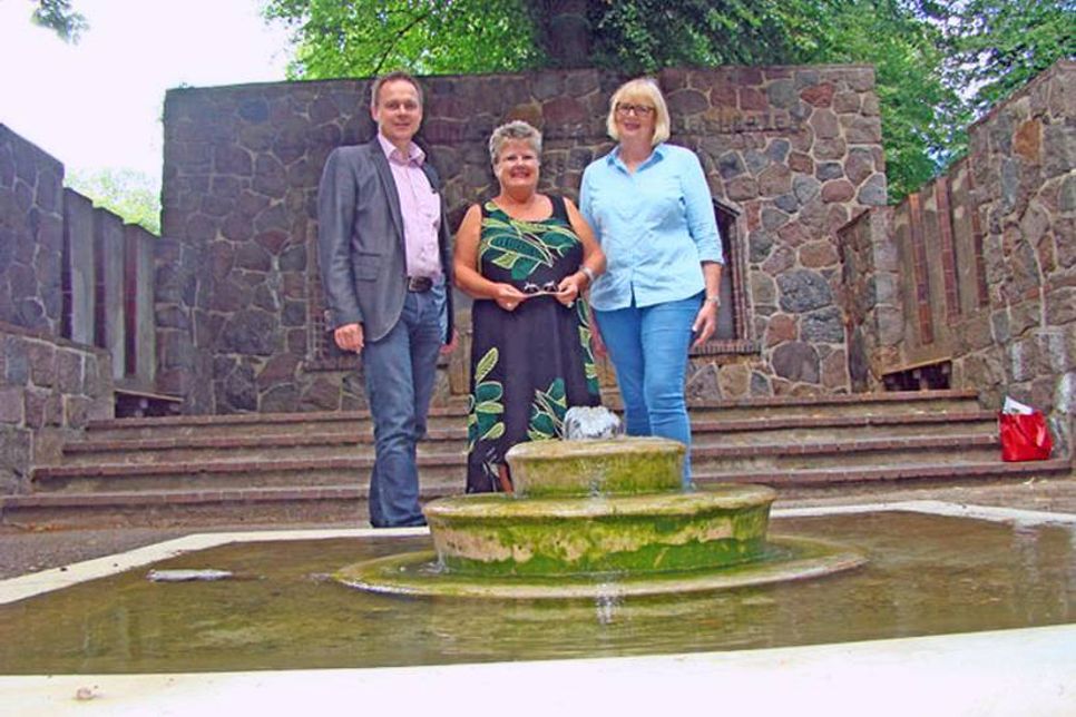 Gitta Stender und Regine Jepp freuen sich mit Bürgermeister Carsten Behnk über die Rückversetzung des Brunnens.