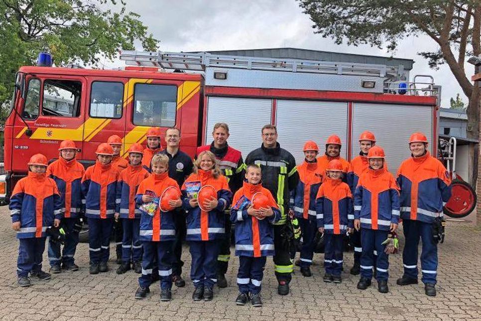 Vorne die drei neuen Jugendlichen aus der Kinderfeuerwehr (Helm in der Hand), dahinter von links David Siegmund, Leiter der KFS80, Sebastian Levgrün, Ortswehrführer der FFS80 und Marc Rollmann, Jugendwart der JFS 80, dahinter das Team der JFS 80.
