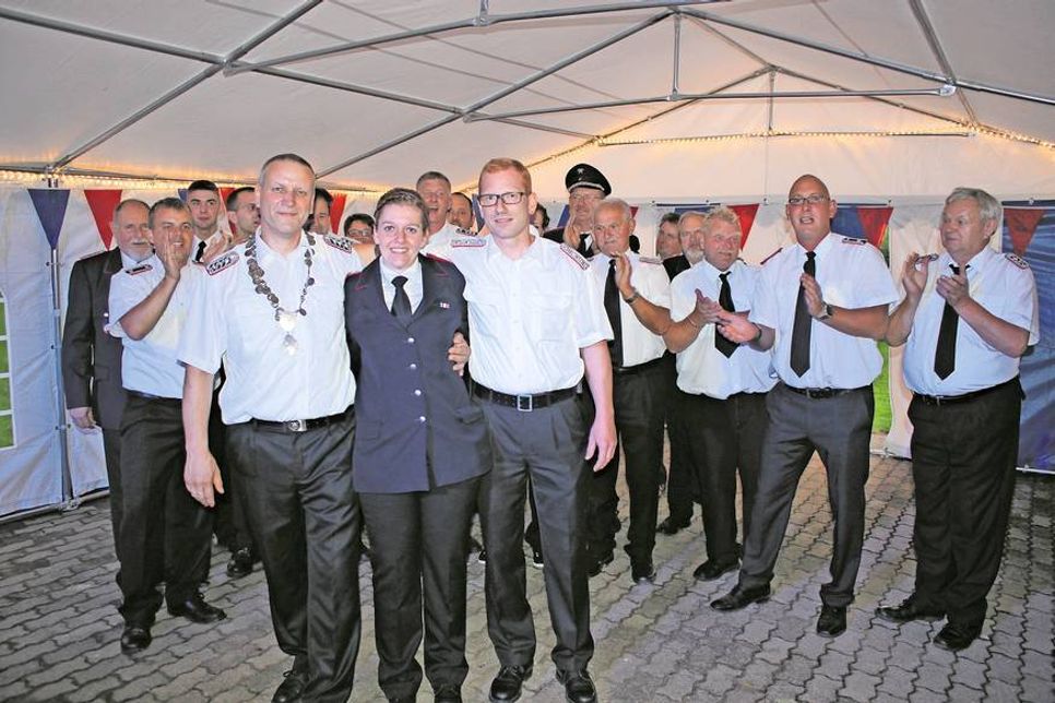 Der neue König Ralf Gurke (lks.) mit Lebensgefährtin Nicole Schmedemann und Wehrführer Frank Paustian vor den Kameraden der Feuerwehr Lensahnerhof.