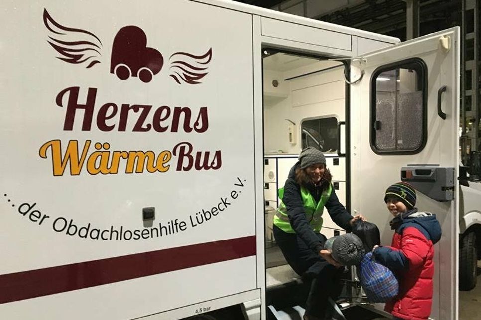 Elias Braun mit der Vertreterin vom Herzenswärme-Bus bei der Übergabe von Schlafsäcken.