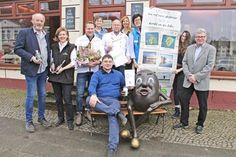 Axel Münster, Obsthof Münster, Gaby Overath, Kirschenholzbrauerei, Alexander Hedegger, Schlossküche Eutin, Corina Schlüter, Schlachterei Schlüter Wankendorf, Harry Heinsen, DEHOGA Ostholstein, Karin Zarp-Menzel, Noctalis Bad Segeberg, Ulrike Leptien, Tourist-Info Plön, Gaye Selcuk, Naturpark, Horst Weppler, AktivRegion. Unten auf der Bank Tim Schnoor, Kalkberg Kaffee Horst Weppler zeigt die Tüte „För to Huus“.
