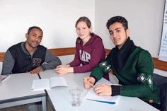 Maru Eshetu aus Eritrea (links) und Kusai Kreem aus Syrien (rechts) lassen sich von Manou Gomlich bei ihren Deutschaufgaben helfen.
