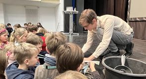 Referent Daniel Lenz von der Technischen Hochschule Lübeck beim Unterschreiben der Studentenausweise der Kinder.