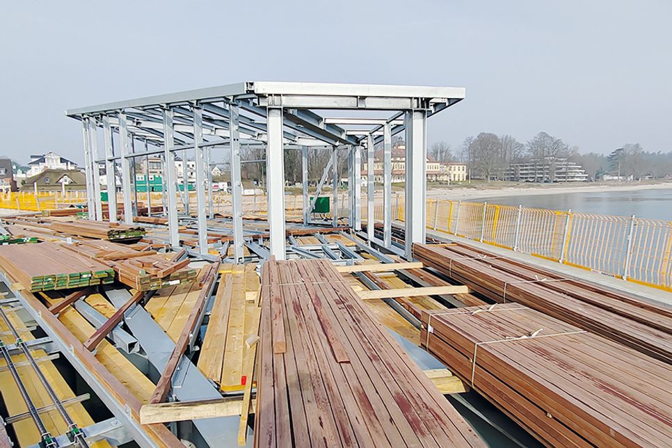 Das Stahlgerüst für den Wetterschutz, in dem ab Sommer auch Trauungen in Haffkrug stattfinden, steht bereits. Davor lagert das harte Bongossi-Holz, das als Bodenbelag verbaut wird.